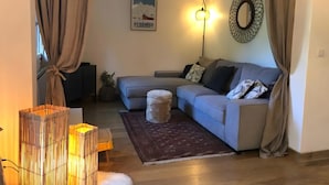 A living room with a sofa, a rug, a wall-mounted light, and a framed picture. - Holiday Home 'L'escale Cauterets' with Mountain View, Private Terrace and Wi-Fi (Cauterets)