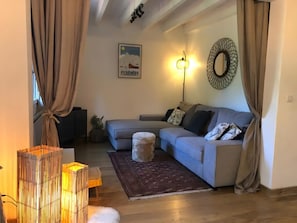 A living room with a sofa, a rug, a wall-mounted light, and a framed picture. - Holiday Home 'L'escale Cauterets' with Mountain View, Private Terrace and Wi-Fi (Cauterets)