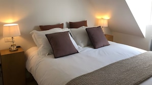 A neatly made bed with white and brown bedding, two bedside lamps, and a window with natural light. - Holiday Home 'L'escale Cauterets' with Mountain View, Private Terrace and Wi-Fi (Cauterets)