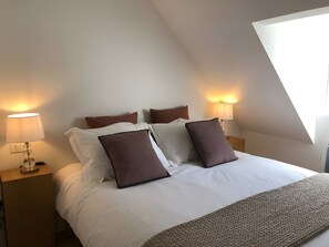 A neatly made bed with white and brown bedding, two bedside lamps, and a window with natural light. - Holiday Home 'L'escale Cauterets' with Mountain View, Private Terrace and Wi-Fi (Cauterets)