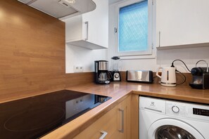 Une cuisine moderne équipée d’une cuisinière intégrée, d’une machine à café, d’un grille-pain et d’un lave-linge.
