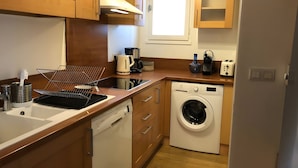 A compact kitchen with a dishwasher, washing machine, and a coffee maker. - Holiday Home 'L'escale Cauterets' with Mountain View, Private Terrace and Wi-Fi (Cauterets)