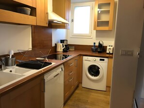 A compact kitchen with a dishwasher, washing machine, and a coffee maker. - Holiday Home 'L'escale Cauterets' with Mountain View, Private Terrace and Wi-Fi (Cauterets)