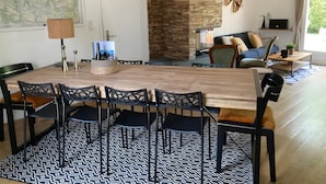 A dining area with a wooden table and chairs, a patterned rug, and a stone wall. - Holiday Home 'L'escale Cauterets' with Mountain View, Private Terrace and Wi-Fi (Cauterets)