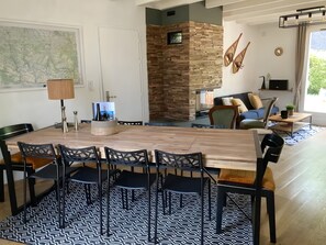A dining area with a wooden table and chairs, a patterned rug, and a stone wall. - Holiday Home 'L'escale Cauterets' with Mountain View, Private Terrace and Wi-Fi (Cauterets)
