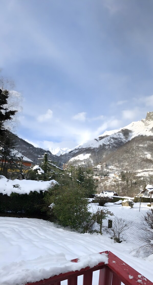 A snowy mountain landscape with a red railing in the foreground.