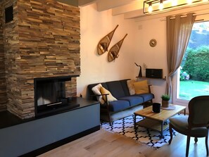 A living room with a stone fireplace, a sofa, a coffee table, and a television.