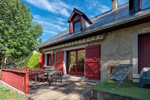 A house with a wooden deck, a dining table, and chairs.