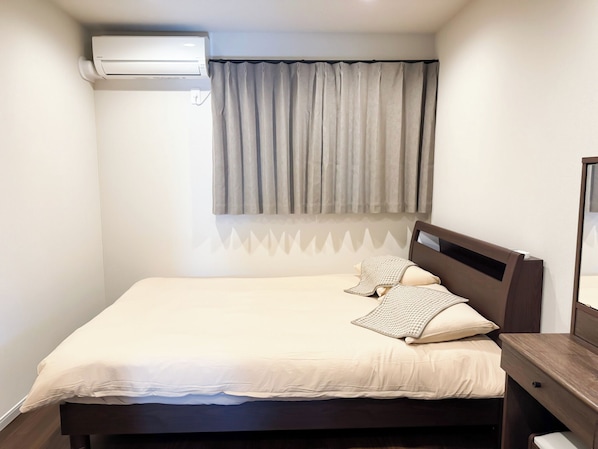 Ein Schlafzimmer mit einem Bett, einem Nachttisch, einem Spiegel und einer Klimaanlage.