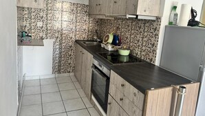 Uma cozinha compacta com painel de azulejos, armários de madeira, uma pia de aço inoxidável e um forno embutido.