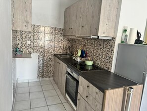 Eine kompakte Küche mit gefliestem Rückspritzschutz, Holdekor-Schränken, einer Edelstahl-Spüle und einem eingebauten Backofen.