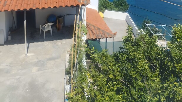 Um edifício à beira-mar com telhado em azulejos, varanda e vista para o mar.