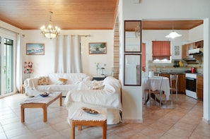 A cozy living room with a sofa, a dining table, a kitchen area with a sink and stove, and a chandelier. - Apartment 'Blue Horizon' with Sea View, Wi-Fi and Air Conditioning (Kranidi)