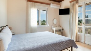A bedroom with a bed, a vanity with a mirror, an air conditioning unit, and a television on the wall.