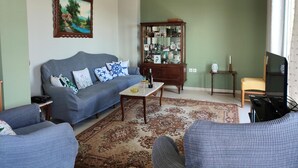 Una sala de estar con sofá, mesa de centro, aparador y televisor.