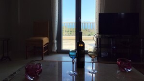 Una habitación con una mesa, una silla, un televisor y un balcón con vistas.