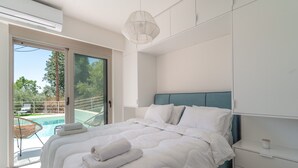Une chambre avec un lit, une table de chevet, un luminaire au plafond et une vue sur une piscine.