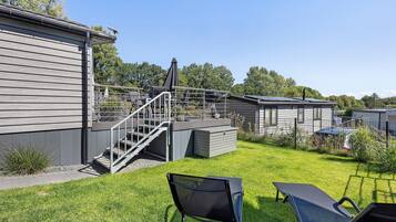 Una propiedad residencial con una zona de estar techada al aire libre, una escalera que conduce a una terraza y un patio cercado.