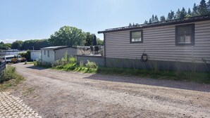 Yhden kerroksen rakennus, jonka edessä on sorapäällysteinen ajotie, ja jonka ympärillä on kasvillisuutta ja muita rakennelmia.