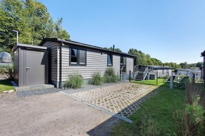 Una casa móvil con entrada pavimentada, patio cercado y un pequeño jardín.