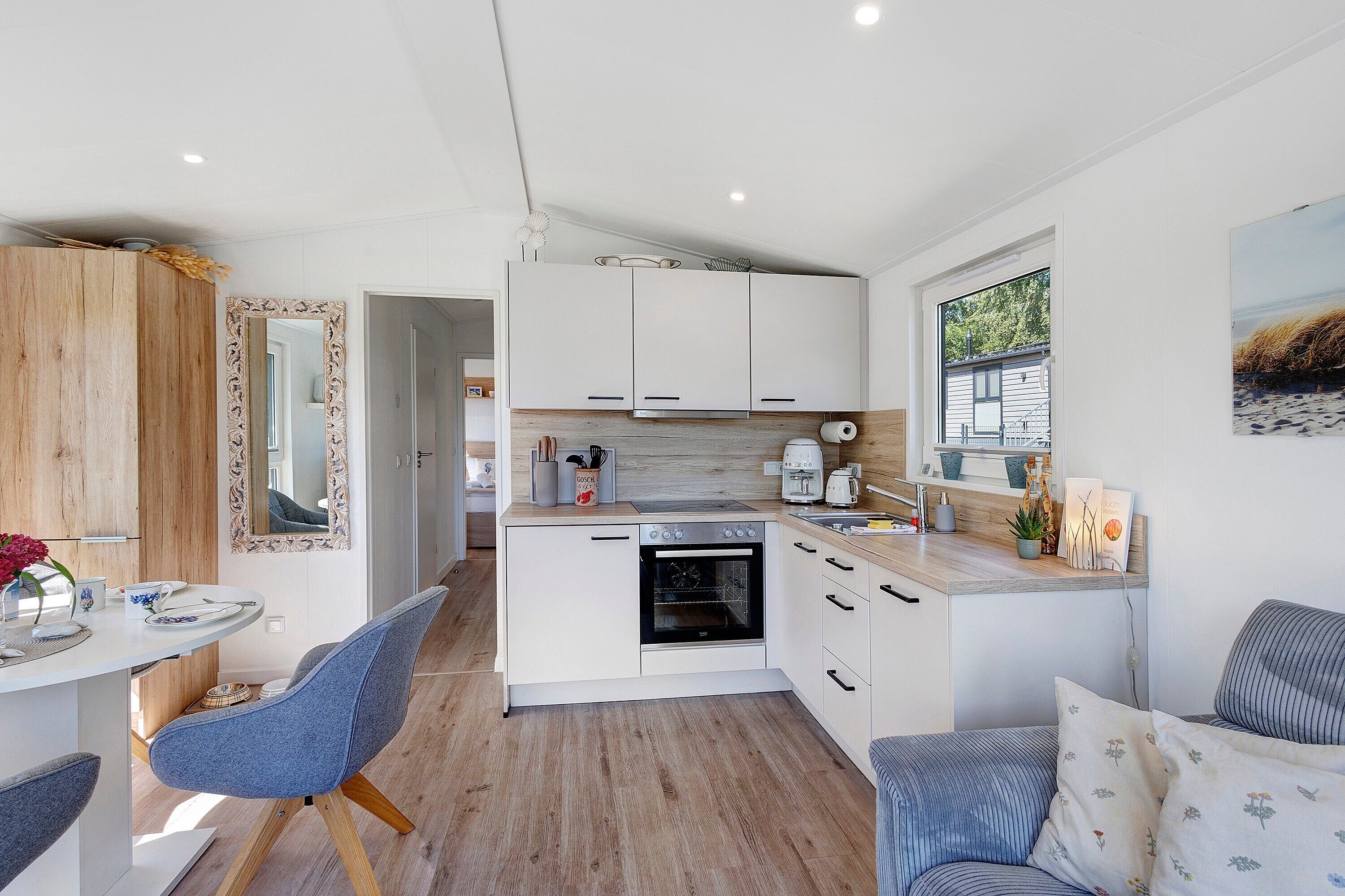A modern kitchen with white cabinetry, a built-in oven, and a window providing a view of the outdoors.