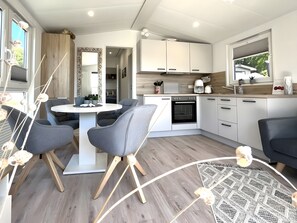 Eine moderne Küche mit weißen Schränken, einem eingebauten Backofen und einem Essbereich mit rundem Tisch und Stühlen.