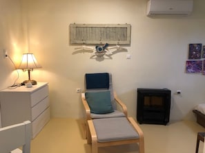 Ein Zimmer mit einem Bett, einem Sessel, einer Lampe, einer Wandheizung und einem kleinen Kamin.