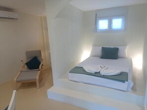 Ein Schlafzimmer mit Bett, Stuhl, Fenster und Treppe.