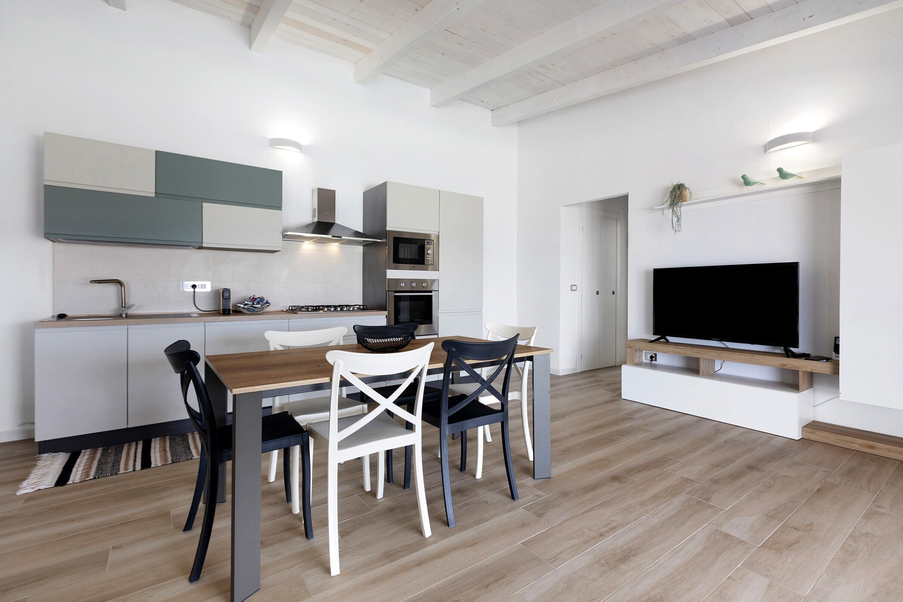 Una cocina moderna con comedor, electrodomésticos integrados y un televisor de pantalla plana.