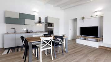 Una cocina moderna con comedor, electrodomésticos integrados y un televisor de pantalla plana.