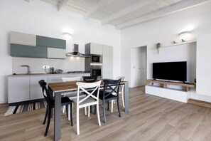 A modern kitchen with a dining area, built-in appliances, and a flat-screen TV.