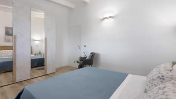 Un dormitorio con una cama, una silla, un espejo y una lámpara de pared.