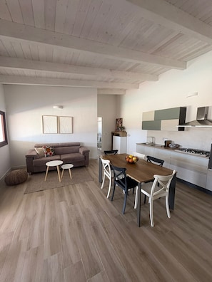 A modern living space with a dining area, kitchen, and a sofa.