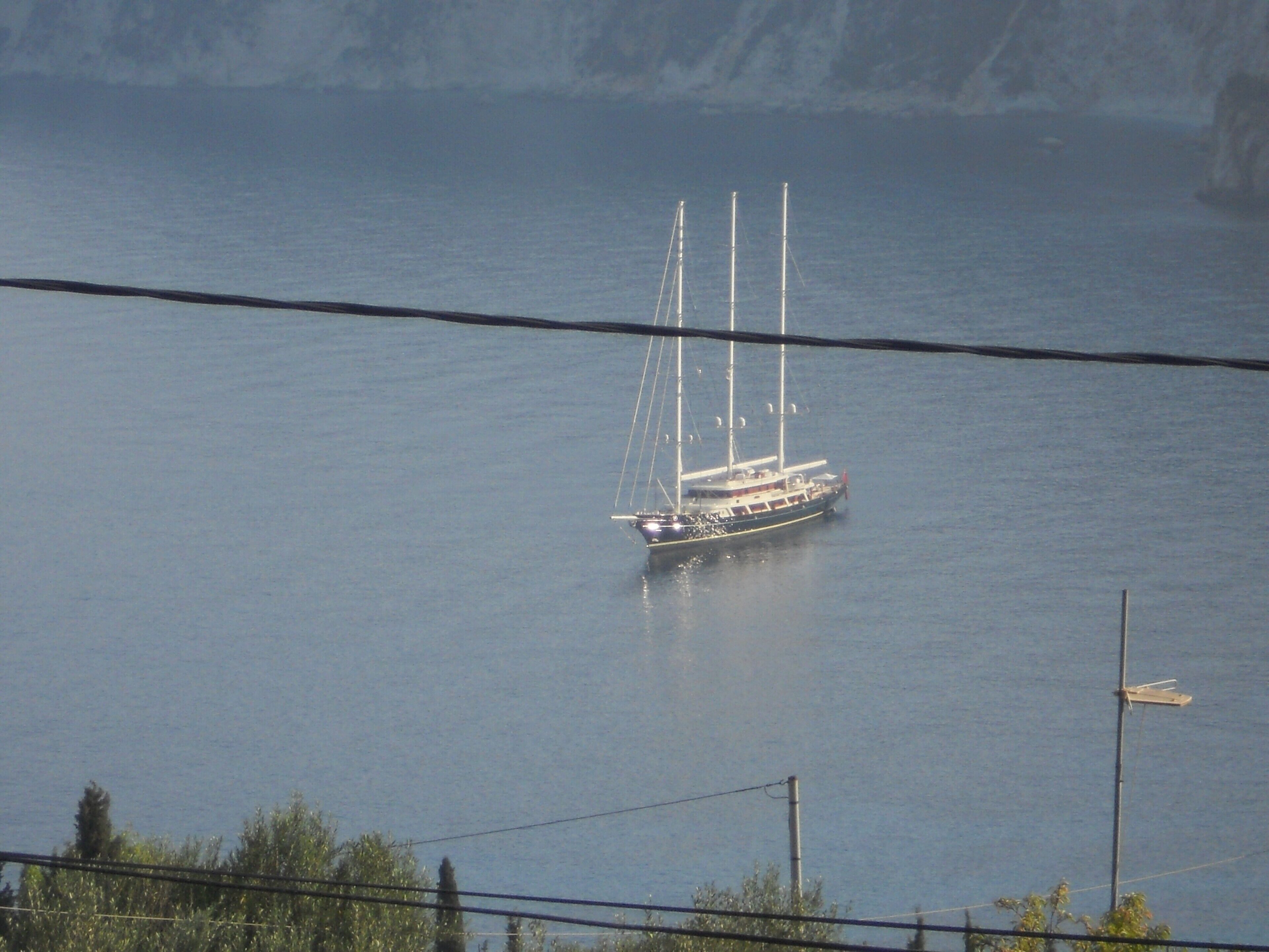 Ein Segelboot auf ruhigem Wasser, umgeben von einer natürlichen Landschaft.