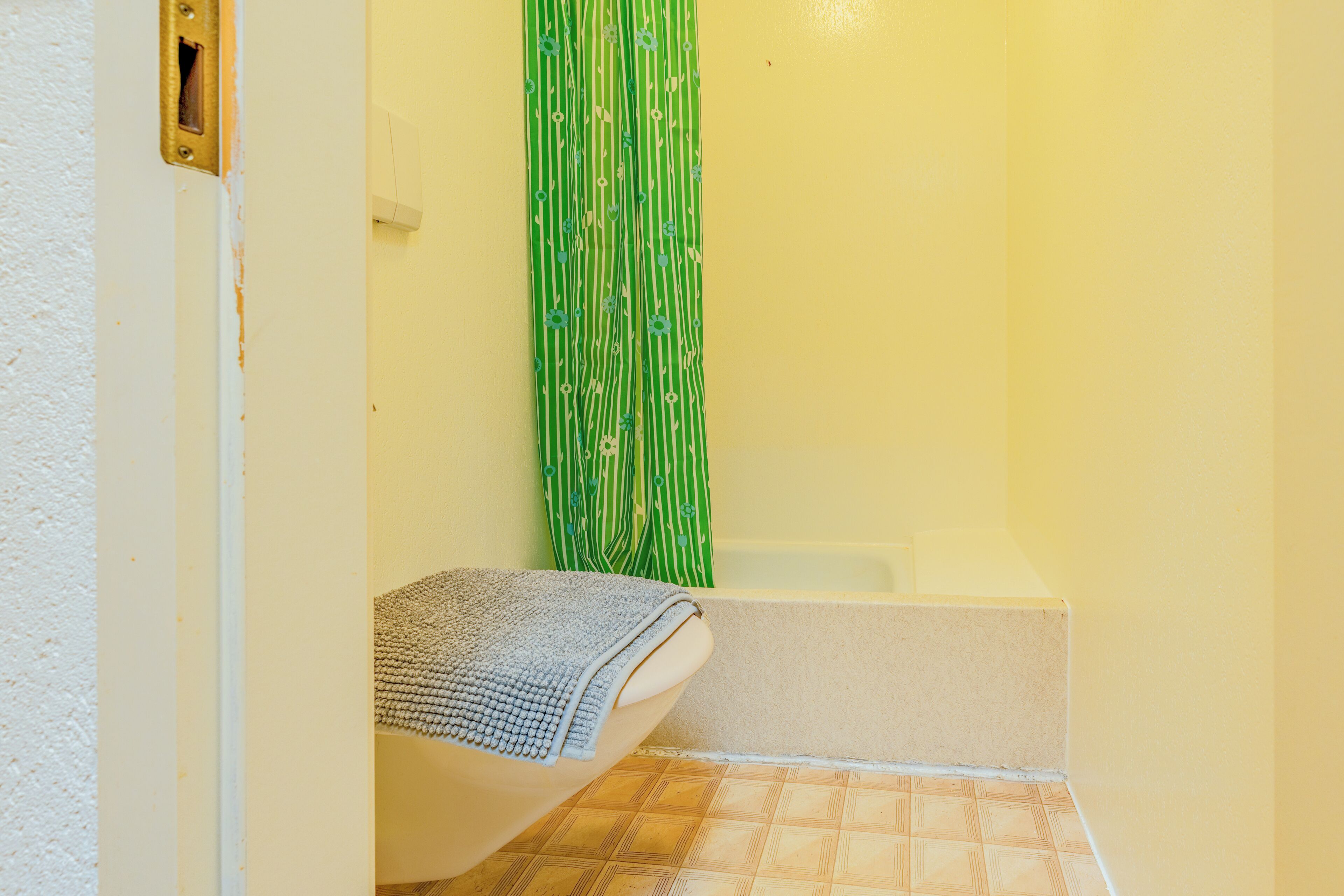 A bathroom with a bathtub, a shower curtain, and a towel.