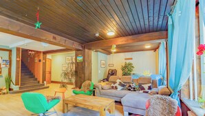 Una sala de estar acogedora con techo de madera, una escalera, un sofá, una mesa de centro y una ventana con cortinas.