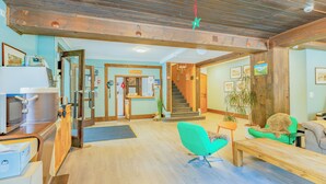 Un vestíbulo amplio con techo de madera, una escalera, un mostrador de recepción y una silla verde.