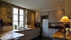 Una cocina moderna con pared de piedra, un ventanal grande y una isla integrada con taburetes.