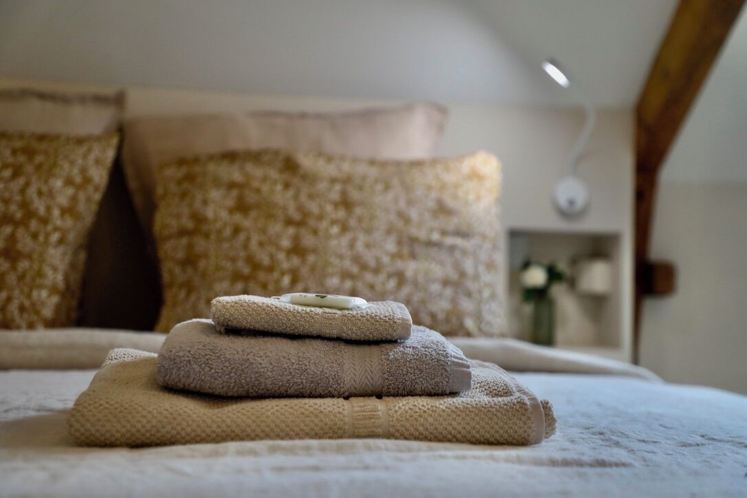 A neatly made bed with a white comforter and multiple folded towels.