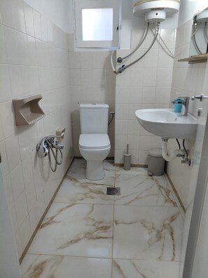 Ein Badezimmer mit Toilette, Waschbecken, Dusche und einem Fenster.