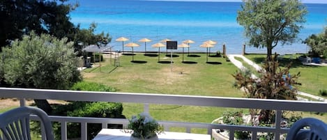 Un balcon avec une table, des chaises et une vue sur la mer.