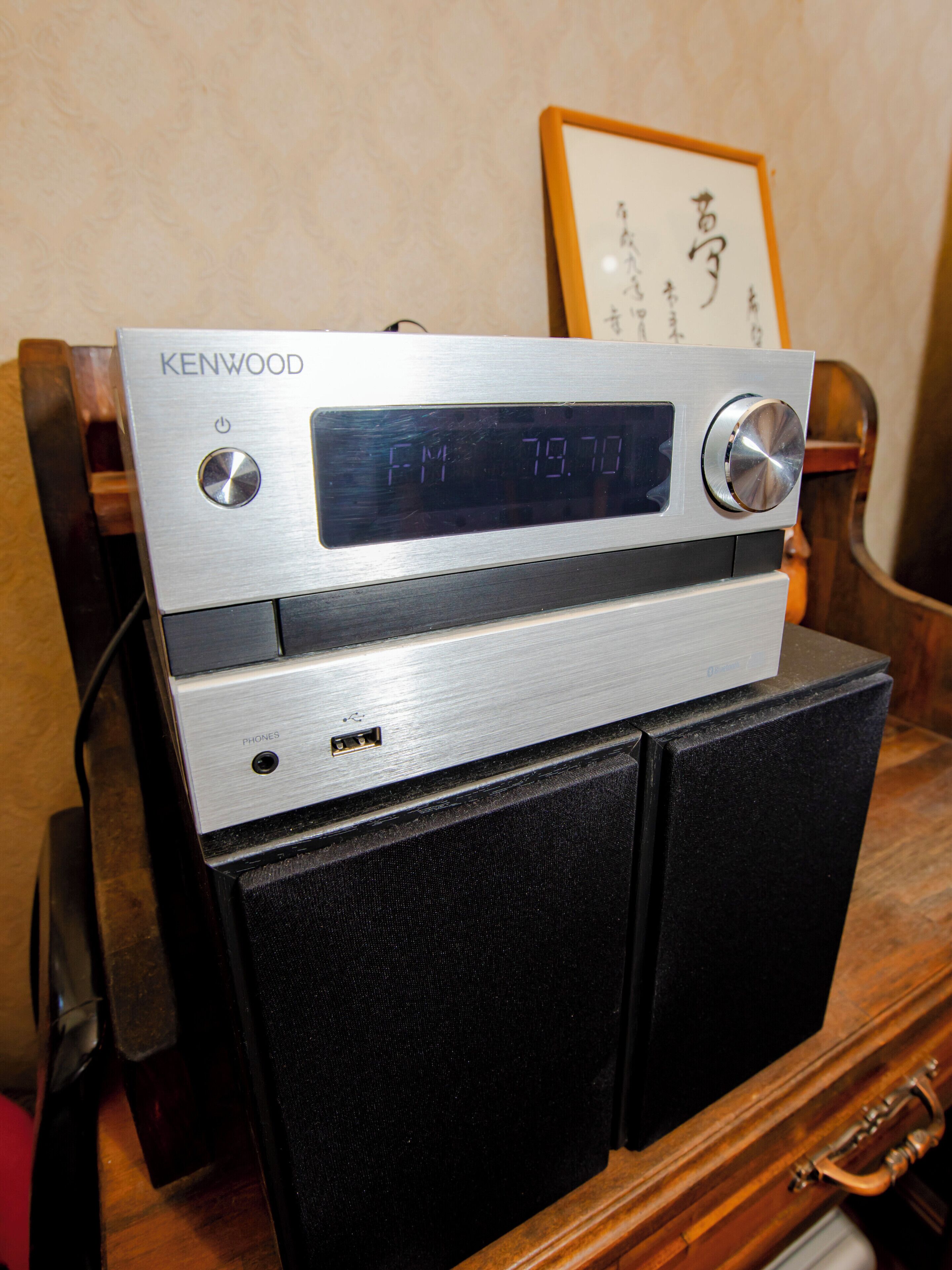 Un radiodispositivo Kenwood sobre un mueble de madera.