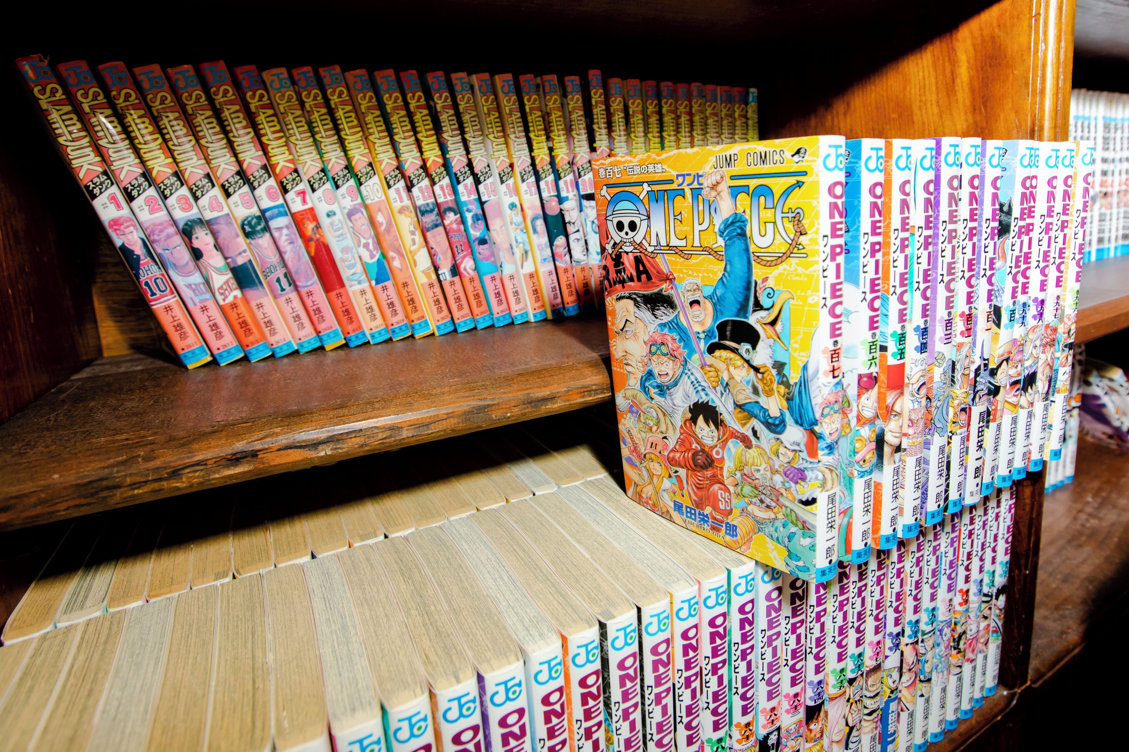 A collection of manga books arranged on shelves and a wooden bench.