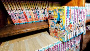 A collection of manga books arranged on shelves and a wooden bench.