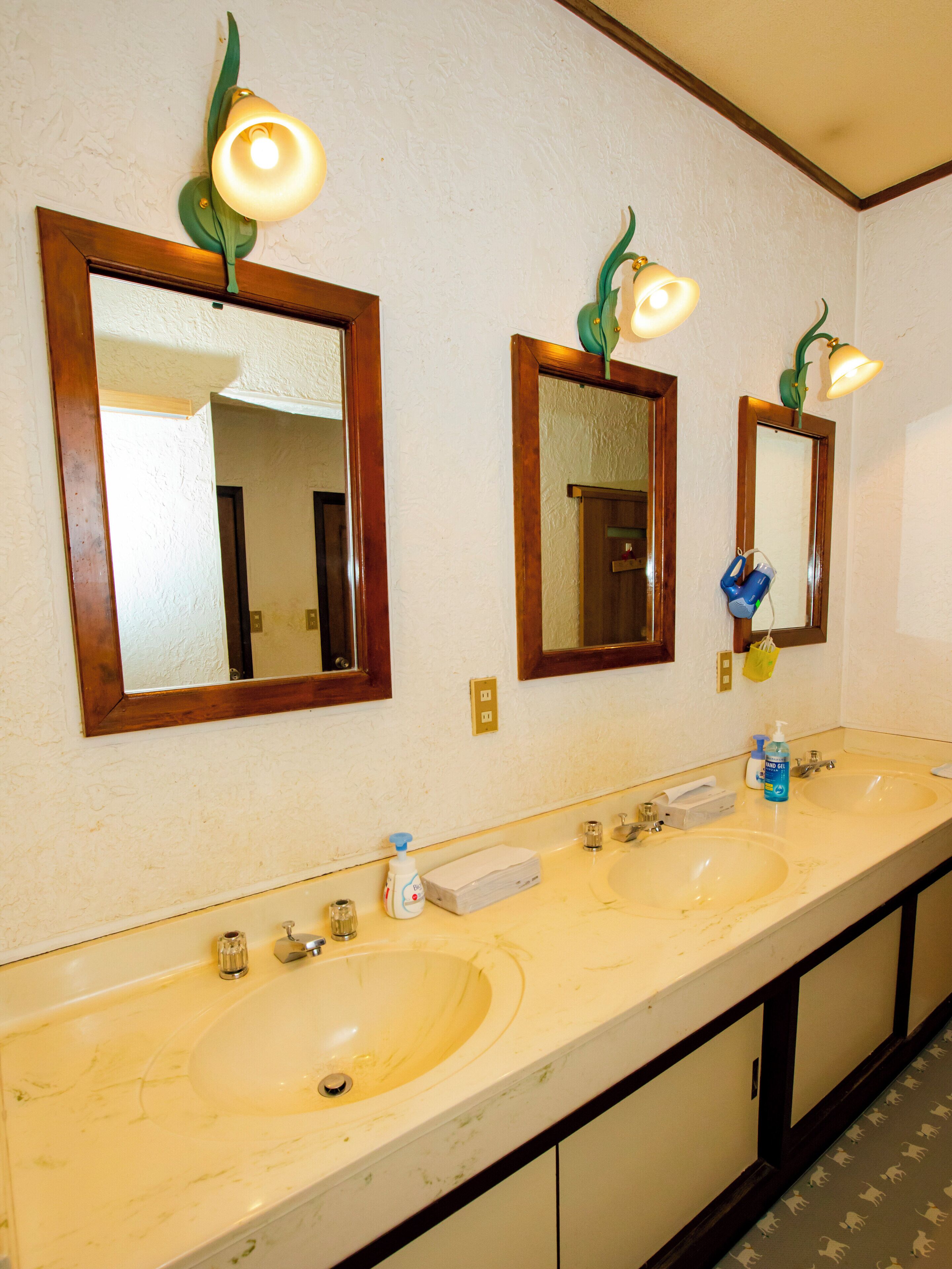 A bathroom with two sinks, mirrors, and wall-mounted light fixtures.