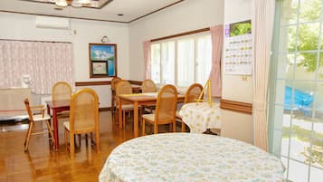 A dining area with wooden furniture, a clock, and a calendar on the wall.