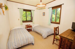 A room with two beds, a desk, a chair, a television, and two windows with curtains. - PENSION SERENADE (Hakuba)