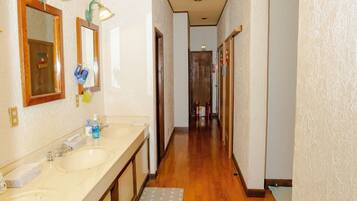 A hallway with two sinks, mirrors, and a wooden floor.