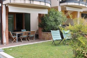 Eine Terrasse mit Tisch und Stühlen, einem Blumentopf und einem kleinen Gartenbereich.