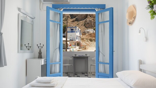 Een slaapkamer met een bed, een klein tafeltje en een open deur naar een balkon.
